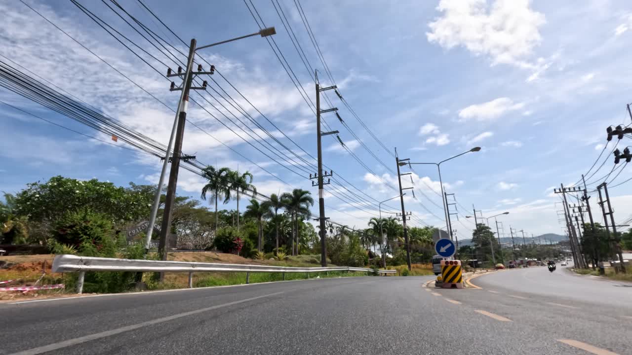 Moving vehicle timelapse along tropical urban road, palm trees, power lines, bright daylight, wide angle