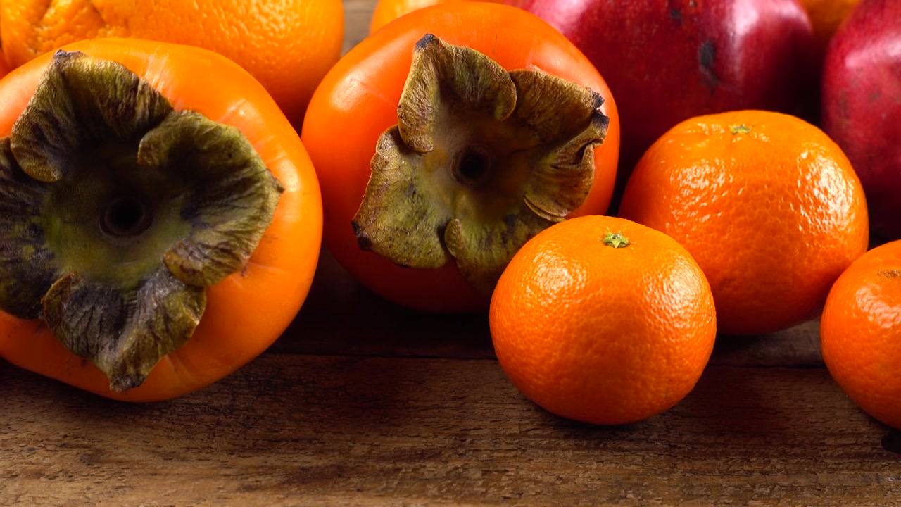 Mandarini, limoni, cachi, arance, mele e melograni su una vecchia tavola di legno vintage
