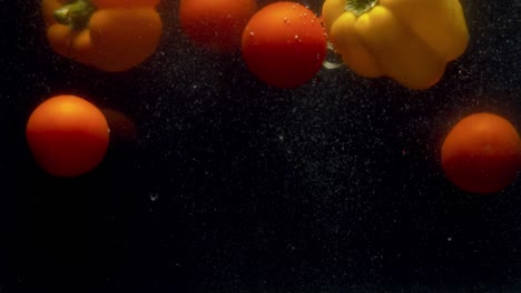 tomatoes and paprika falling into the water