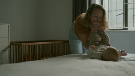 mother playing with baby on bed