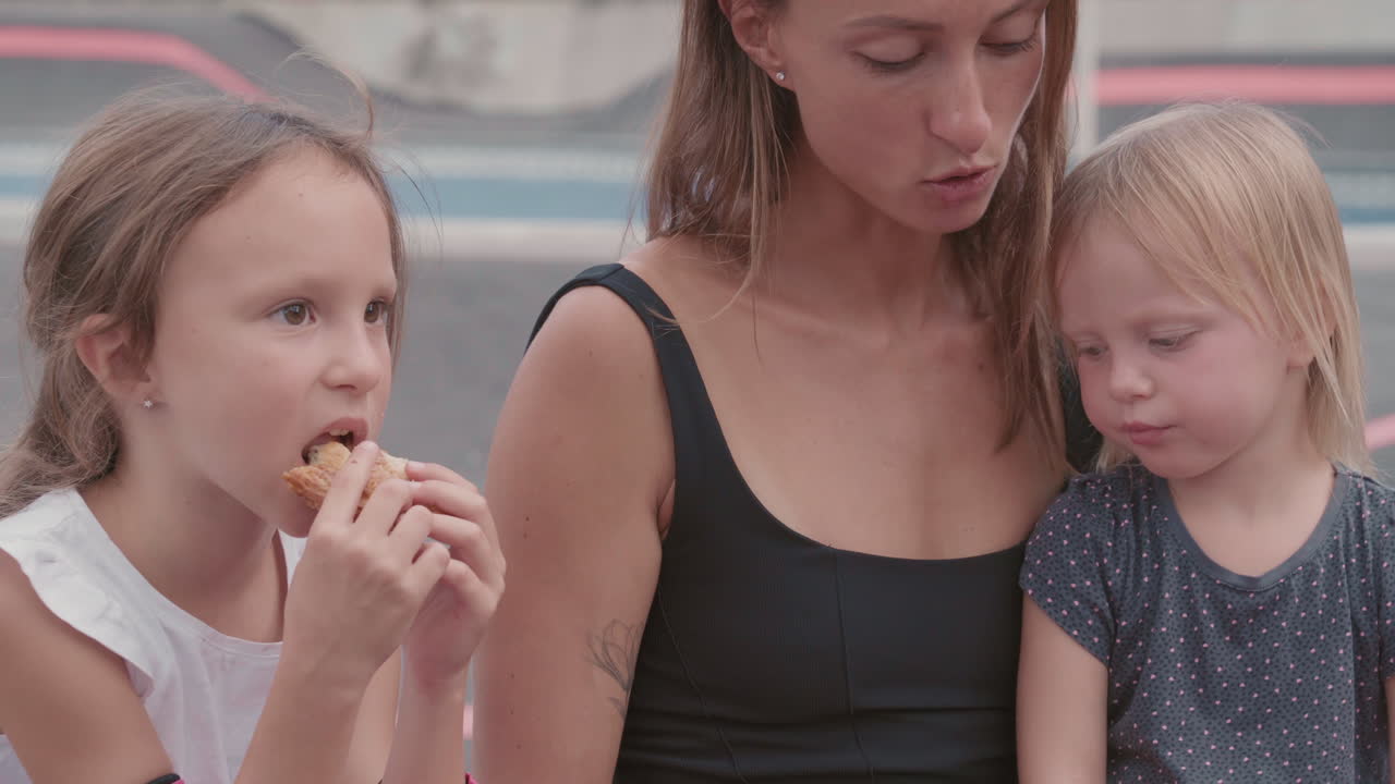 어머니 와 두 자녀 가 야외 에서 식사 하고 있다