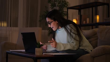 mujer celebrando el éxito en línea tarde en la noche en la computadora portátil