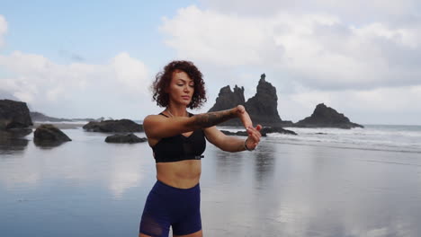 slow motion showcases a serene moment of a young, slim woman practicing stretching and yoga by the ocean, gazing into the distance