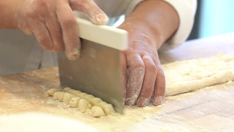 Manos-Humanas-Modelando-Un-Trozo-De-Pasta-Fresca-Y-Haciendo-Un-Tipo-Típico-De-Comida-Italiana