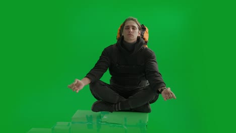 man meditating in lotus pose on green screen