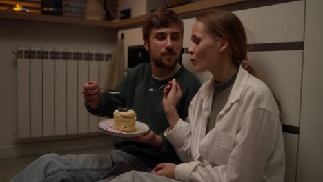 una pareja disfrutando de un pastel en la cocina.