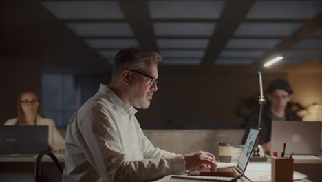 senior businessman working on laptop in office at night