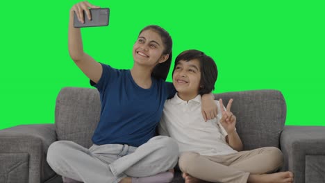 Happy-Indian-sibling-clicking-selfies-Green-screen