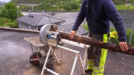 male european using electric saw to cut firewood to prepare for upcoming winter and energy shortage - static clip with no face