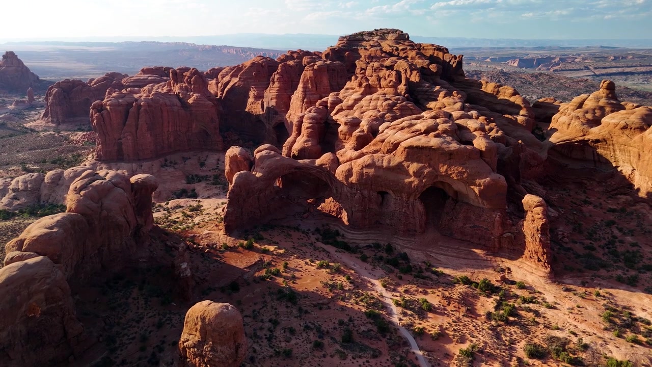 Fantastiske arkivopptak fra Arches nasjonalpark USA en lys ettermiddag. Det strålende sollyset belyser de majestetiske røde sandsteinsformasjonene og ørkenlandskapet under en klar blå himmel.