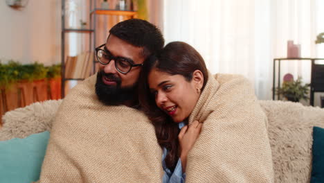 indian family couple man woman hugging under warm blanket at home enjoying quiet cozy time together