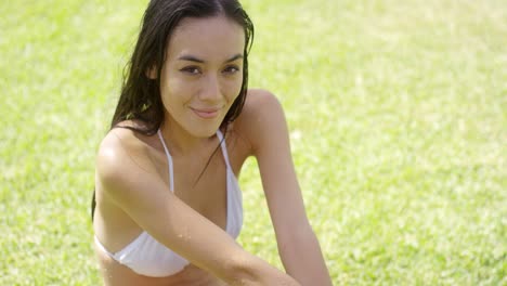 Pretty-brunette-sitting-on-green-lawn