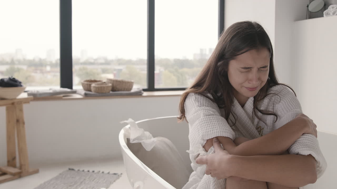 Sad Woman Crying While Sitting In The Bath In A Modern Bathroom At Home