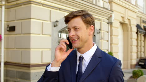 Portrait-male-professional-with-phone-at-street.-Guy-talking-cellphone-outdoors