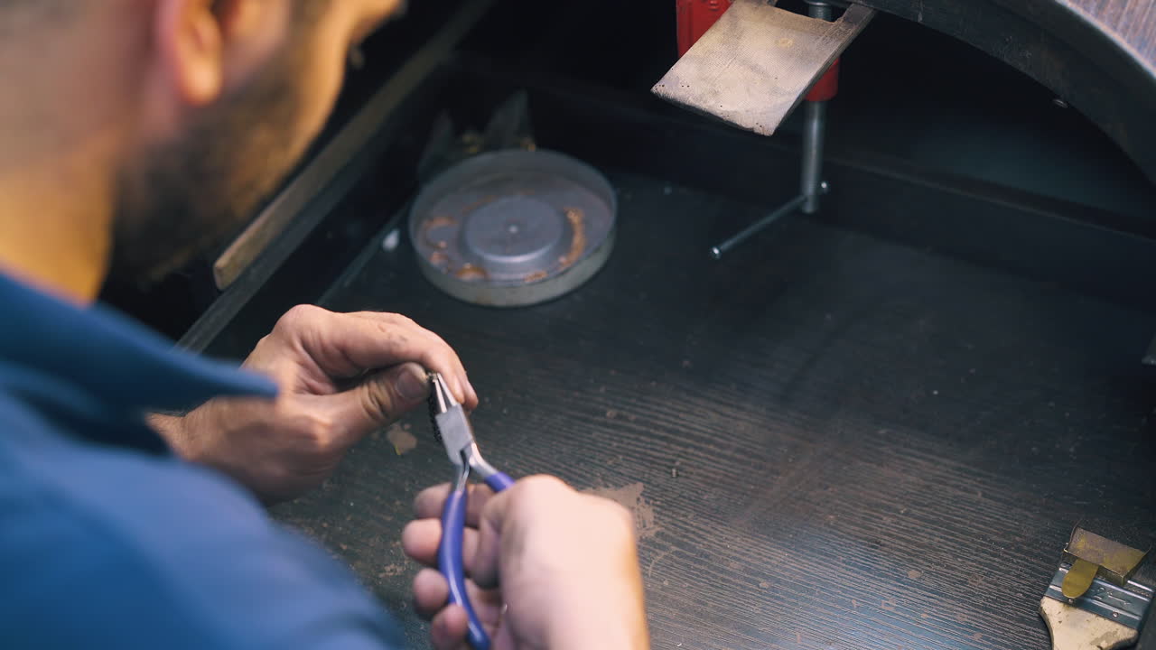 joven joyero trabaja con espiral de oro en la mesa de cerca