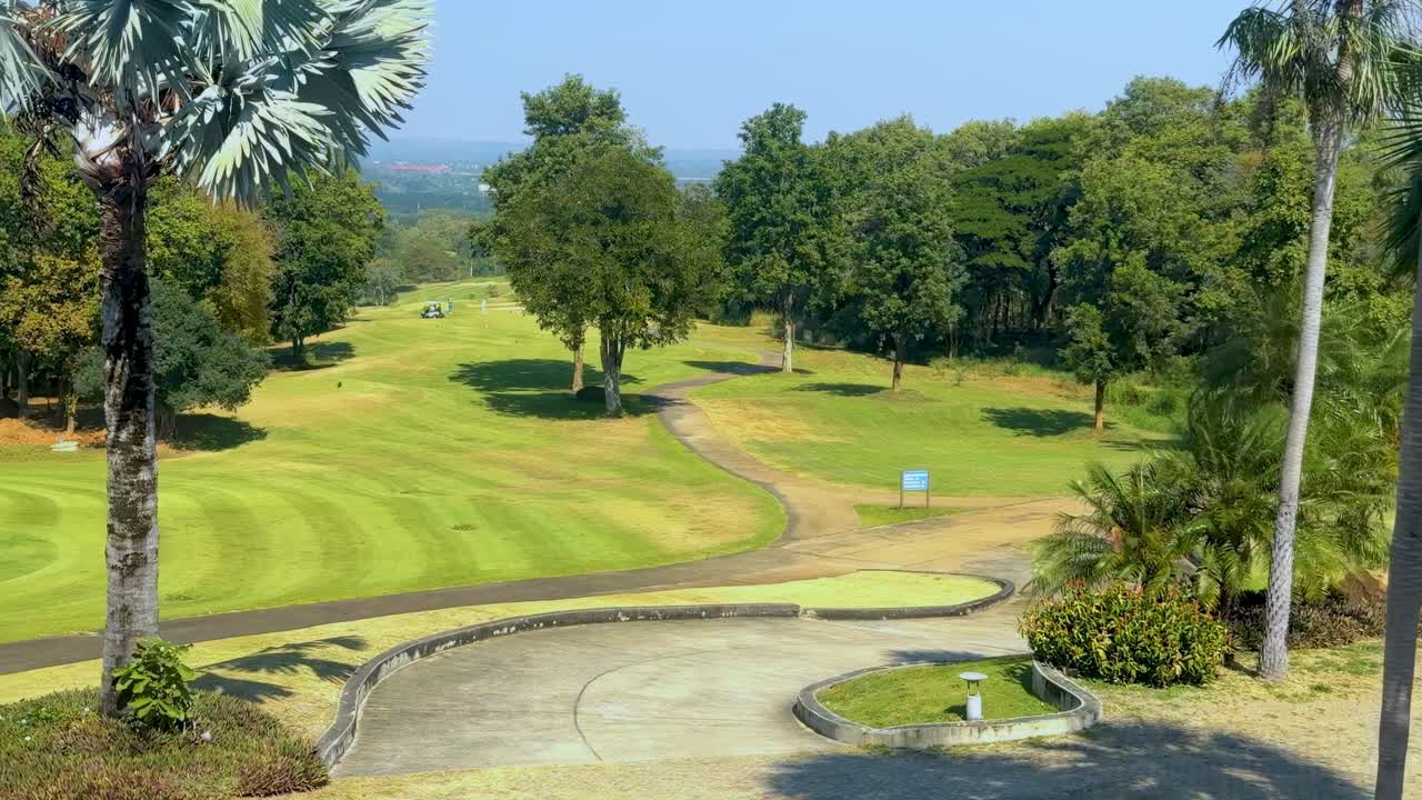 A scenic view of a golf course featuring lush greenery, trees, and a winding pathway.