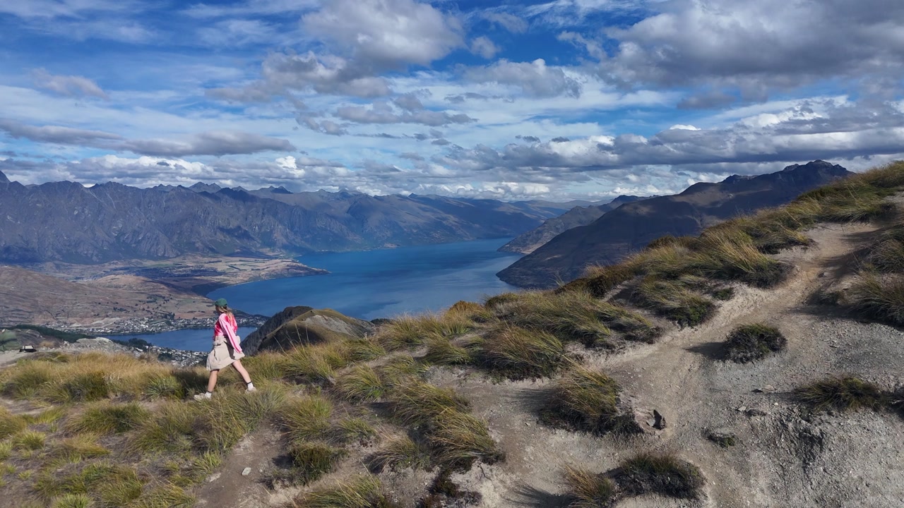 Hiker descends mountain ridge slope above Queenstown in New Zealand