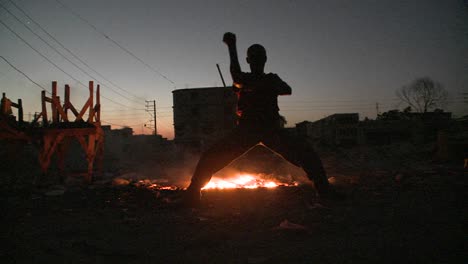 a man dances in silhouette in front of a fire 1