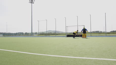 female hockey player practicing on field, goalie diving to block shot