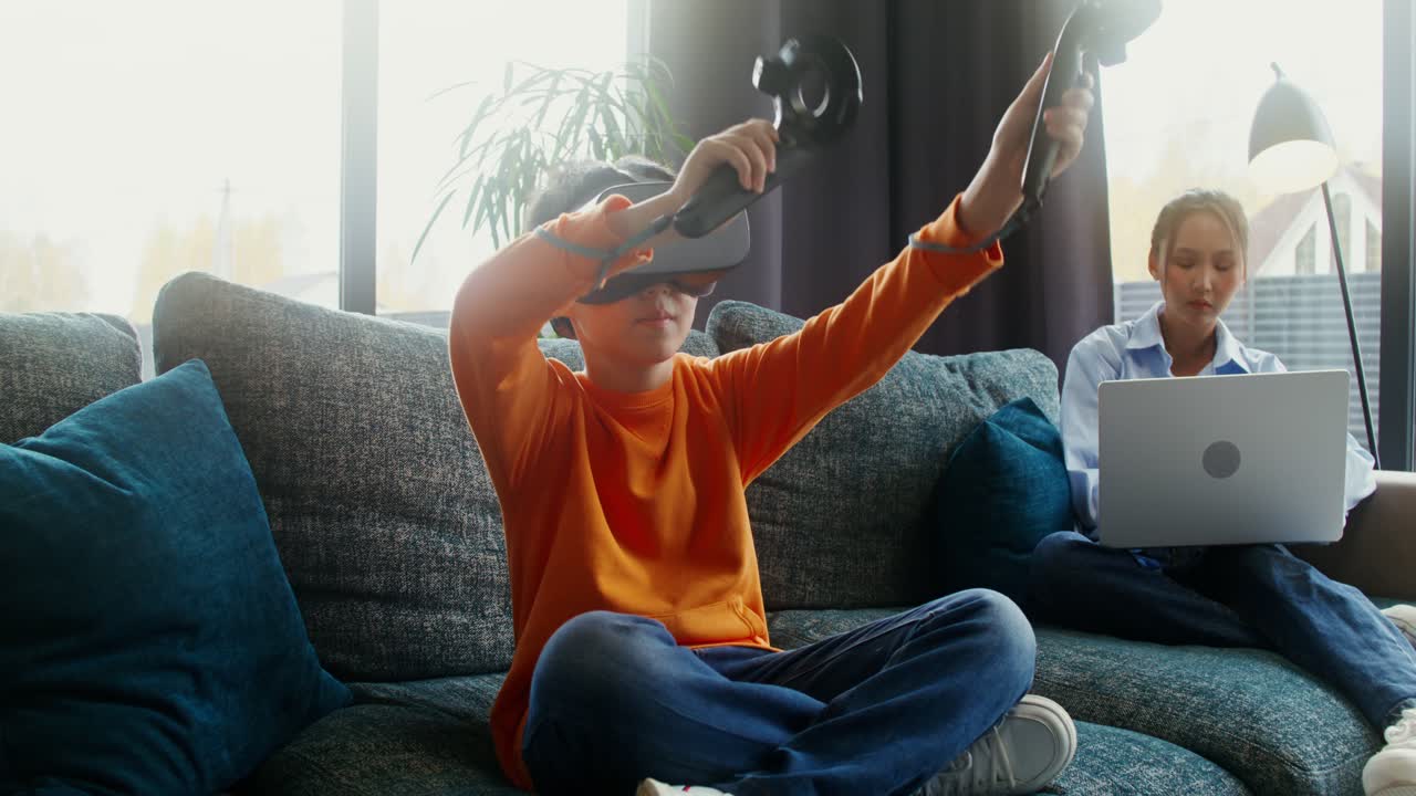 Boy playing VR games while woman works on laptop
