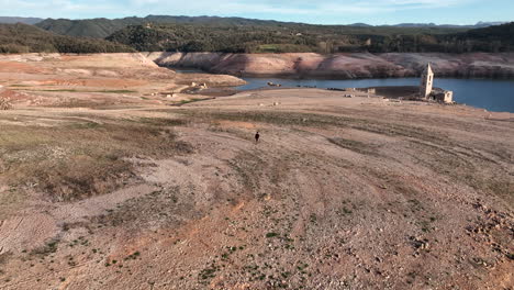 hombre caminando por tierra seca, pantano en el embalse de sau, cataluña, españa