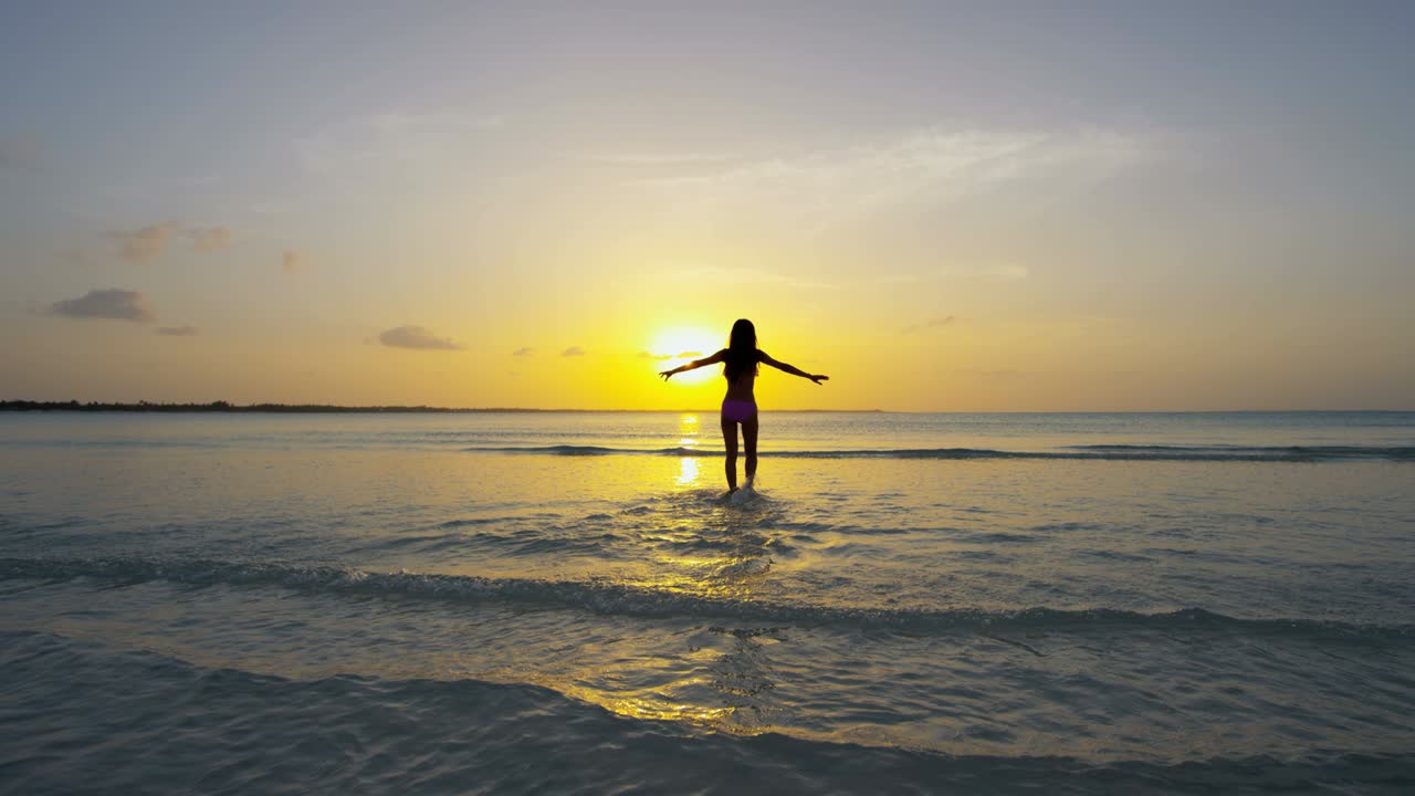 chica étnica descalza bailando despreocupada en una playa tropical