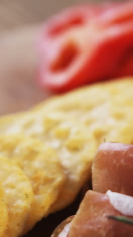 cheese, crispy biscuits and meat on wooden board