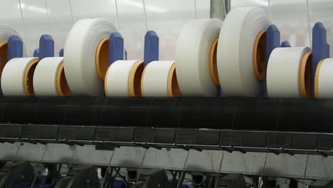máquina de hilado que opera de cerca con bobinas de hilo blanco