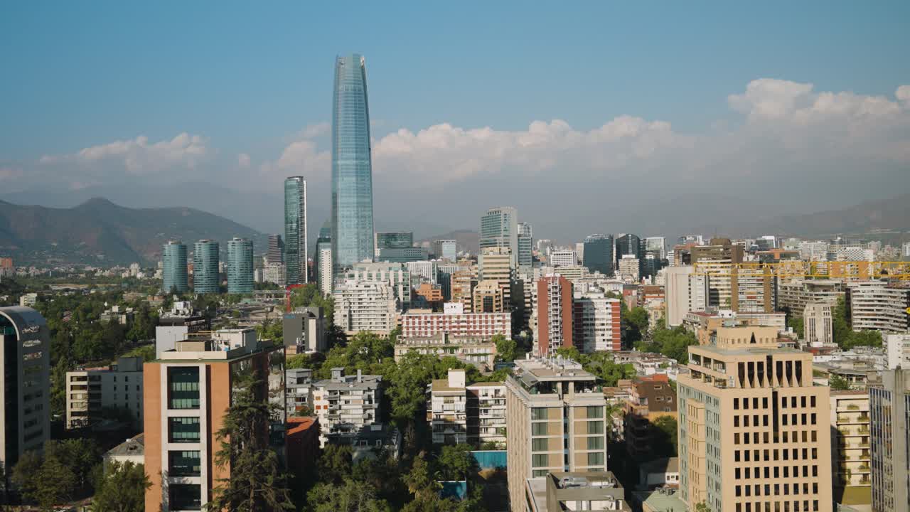 Skyline di Santiago del Cile, quartiere di Providencia, con Gran Torre Santiago (Costanera Center) che si erge sopra i moderni grattacieli e le colline delle Ande sotto un cielo azzurro.