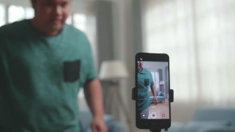 asian man blogger shoots video content for social networks and shows focus on the smartphone camera, close-up, magician with red ball