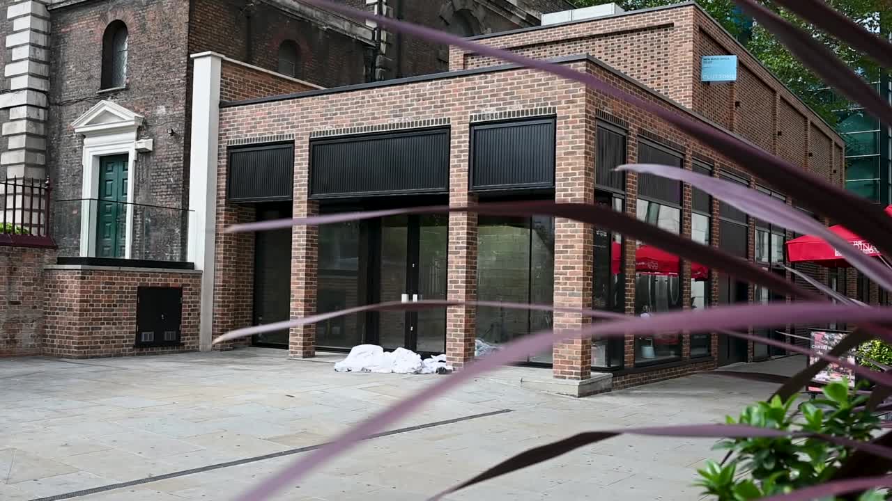 Exterior view outside The Aldgate Centre in London, UK, showing modern architecture, a busy urban setting, and everyday city life