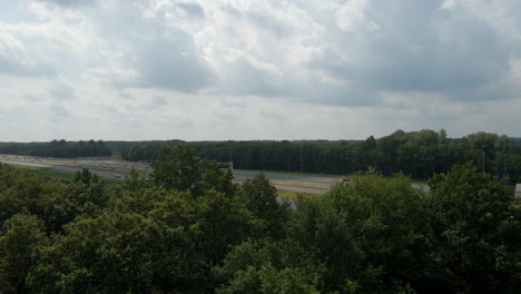 Jib-up-behind-lush-green-trees-and-revealing-a-busy-highway