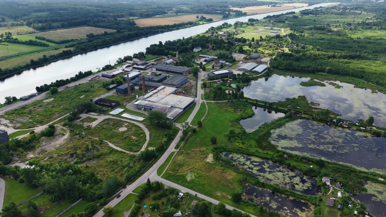 Drone gently turns right above industrial site beside Lielupe, Kalnciems, Latvia