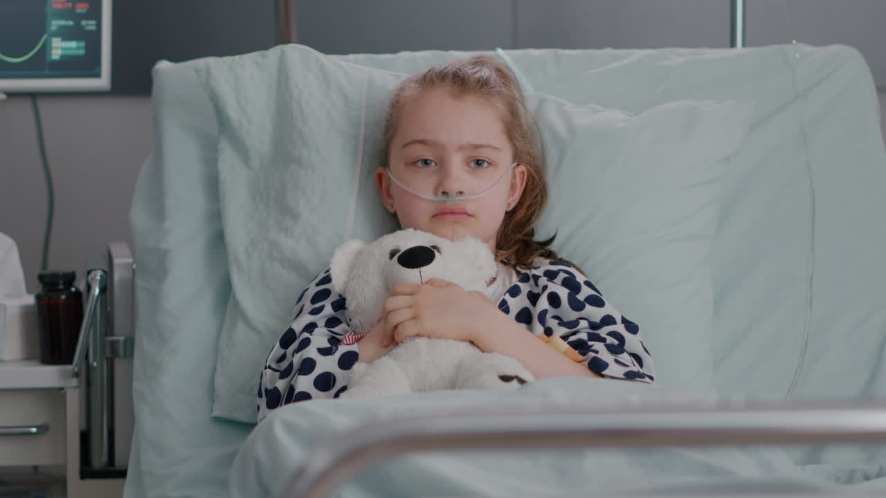 Portrait of lonley sick little child resting in bed holding teedy bear in hands