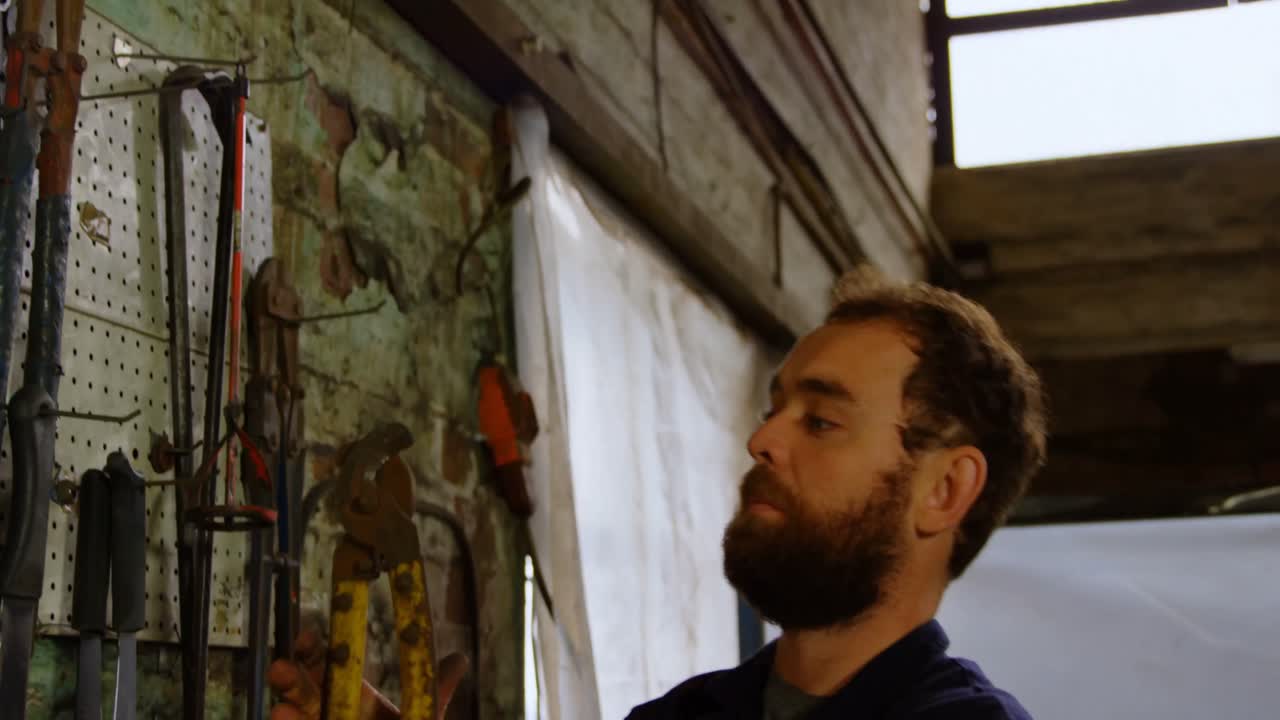 Fabbro che controlla gli attrezzi in officina 4k