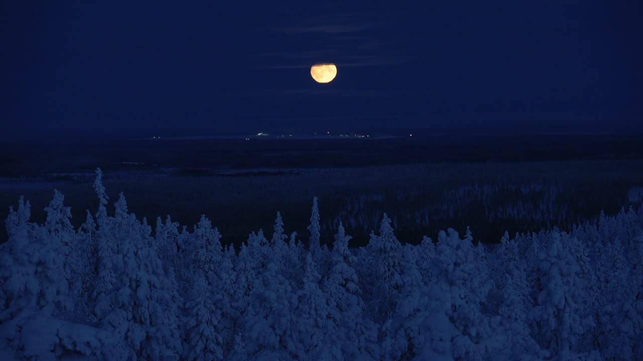 The romantic moonlight over the dark, white landscape of Lapland, Finland