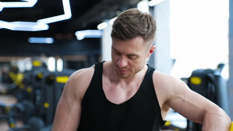 handsome bodybuilder after training. young sportsman with muscular body rests in the gym. portrait of an athlete breathing hard after workout.