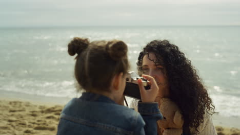 madre y hija tomando fotos en la playa. familia relajándose juntos en la costa.