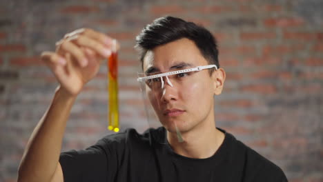 asian medical student looks at test tube with liquid in lab