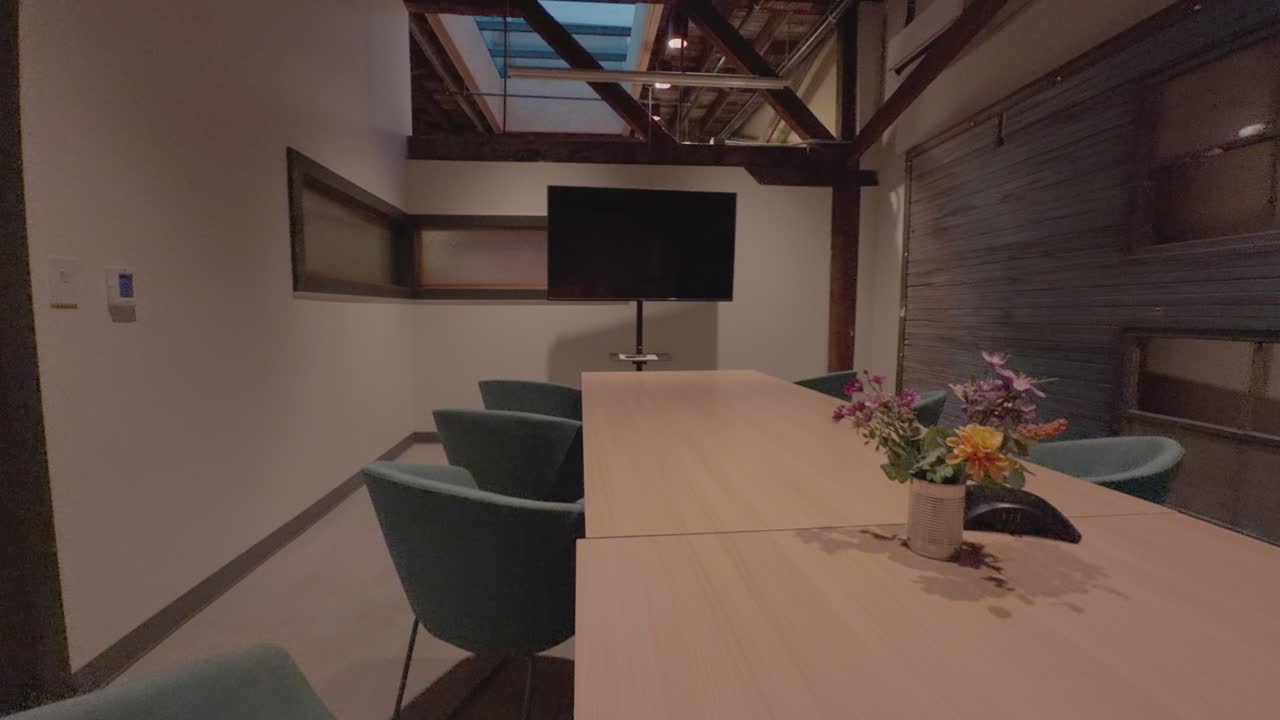 Zoom lento y constante hacia un monitor en un espacio de trabajo de sala de conferencias moderna y vacía