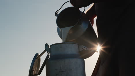 farmer pours milk into can