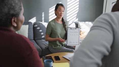 Happy-asian-female-counselor-advising-to-african-american-senior-couple-sitting-on-sofa