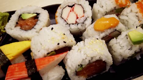 top view sushi tray assorted caviar on top of a california roll, dynamite roll, seattle roll, some wild salmon seaweed white rice black sesames avocado crab imitation ginger soy sauce wasabi yum