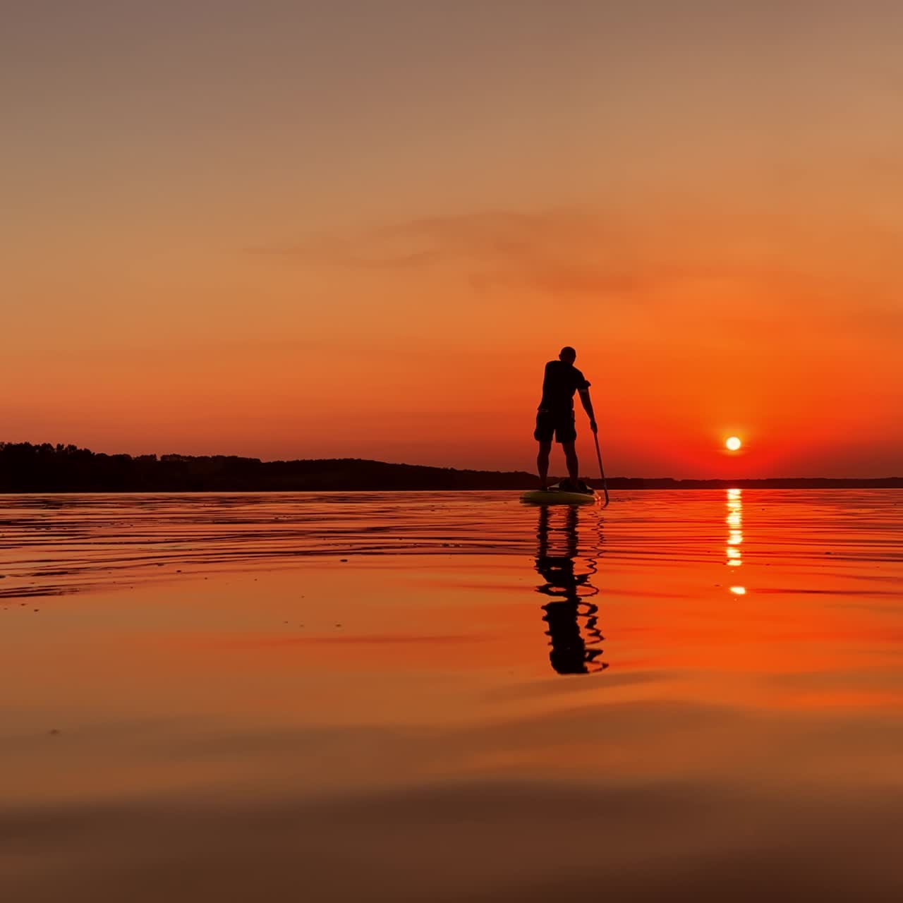 Active time spending in the summer evening time. Male sup boarding on the river at sunset