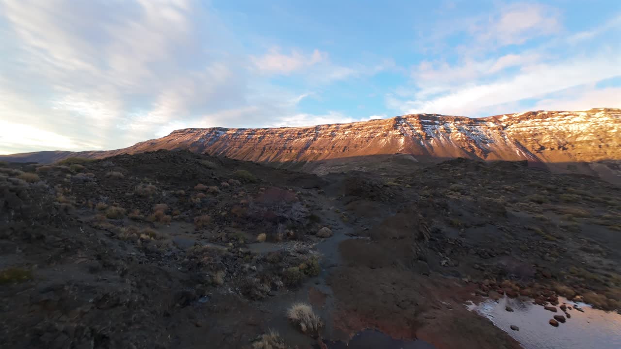 A thrilling, low-altitude FPV drone shot flies close to the turbulent, cascading water of the unique Salto del Agrio waterfall in Argentina at sunset, revealing its powerful flow