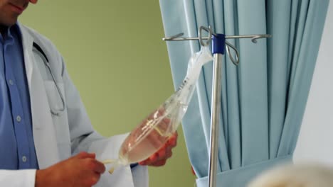 Médico-Examinando-El-Goteo-Intravenoso-De-Un-Paciente