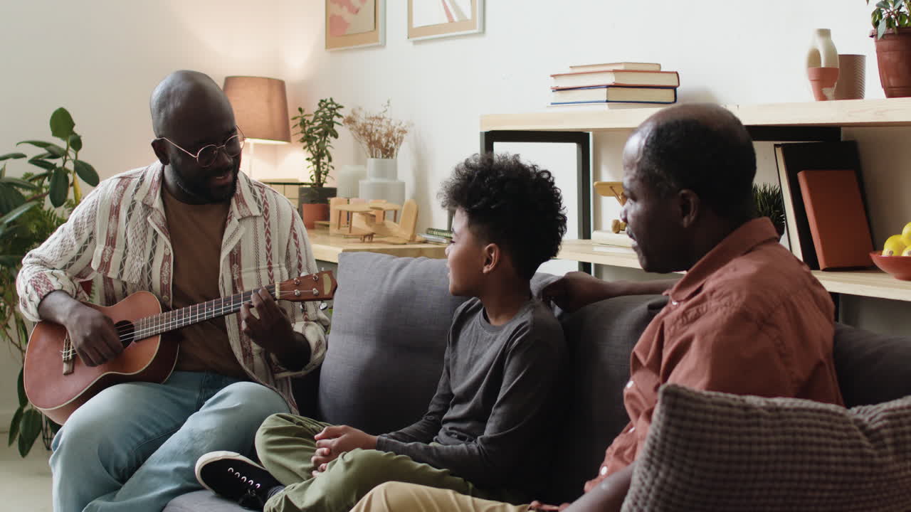 Black man playing ukulele for family at home