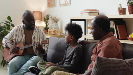 black man playing ukulele for family at home