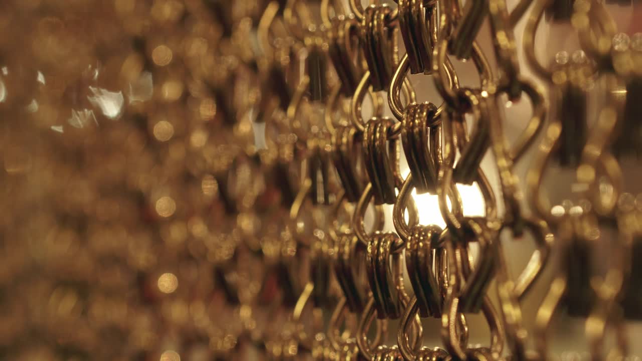 긴 금 사슬의 느리고 부드러운 움직임, 균일한 스, 휴식을 위한 금색 배경, 명상, 휴식, 진정시키기 위한 질감, 반이는 빛, 아래에서 위로 보이는 광경, 흐릿한 빛.