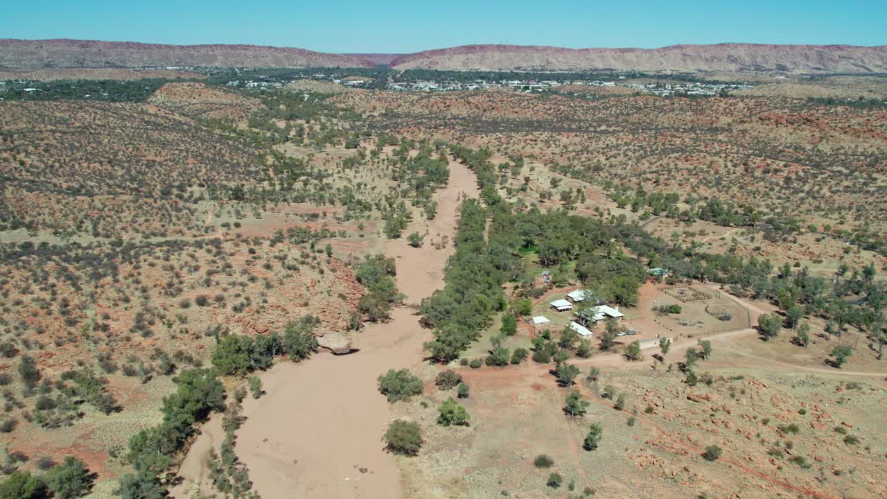 Drone view of the dry Todd River and Telegraph Station on the right, with Alice Springs, Mparntwe, in the distance. Northern Territory, Australia. August 2022.